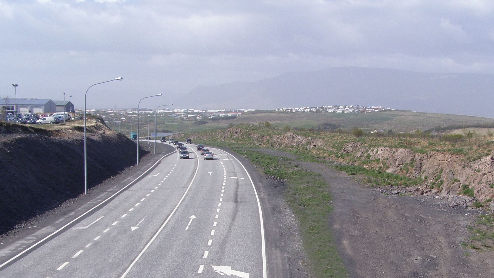 A curved roadway with street lamps and cars