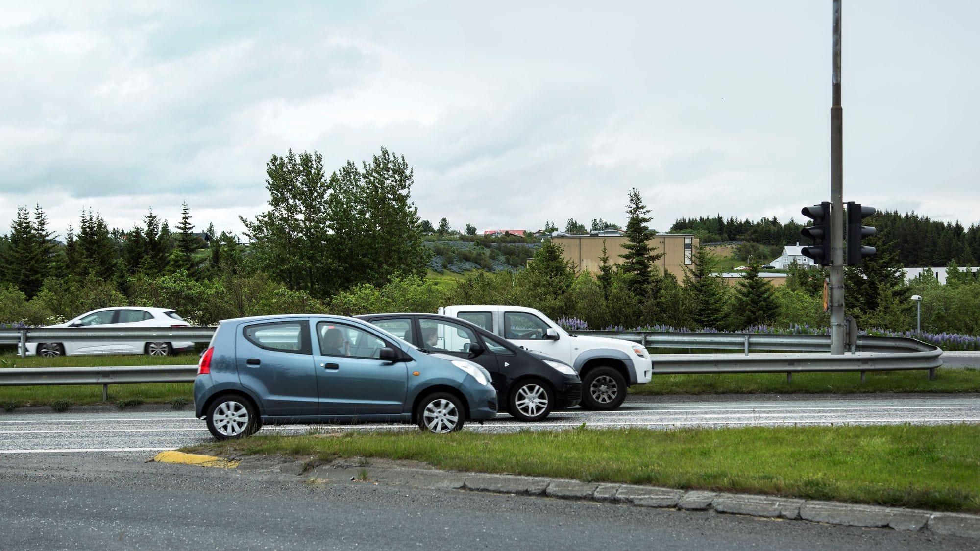 Bílar að keyra á umferðargötu, Elliðárdalur í bakgrunn
