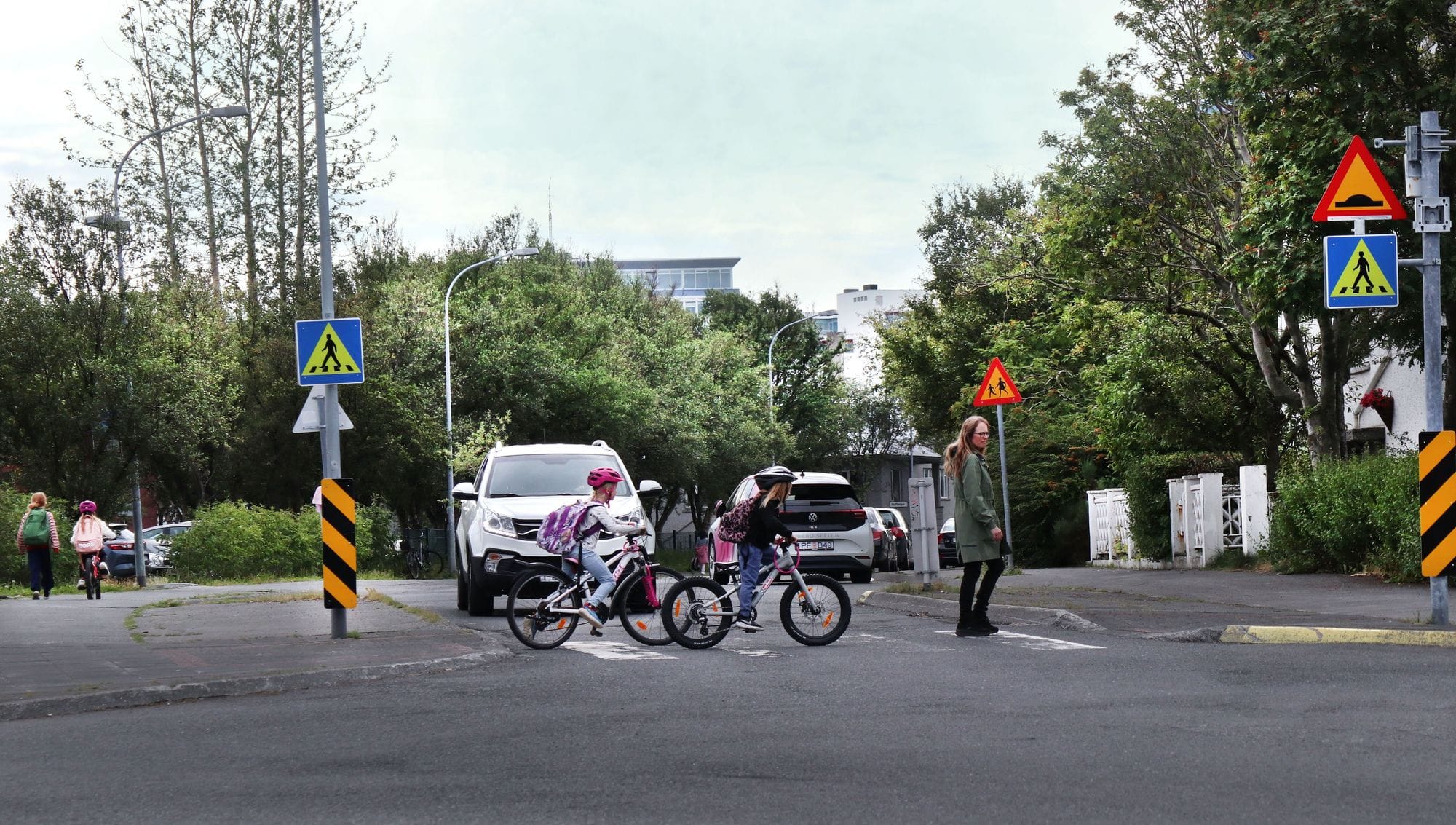 Gangbraut í Reykjavík, börn að fara yfir og bíll stöðvar fyrir þeim