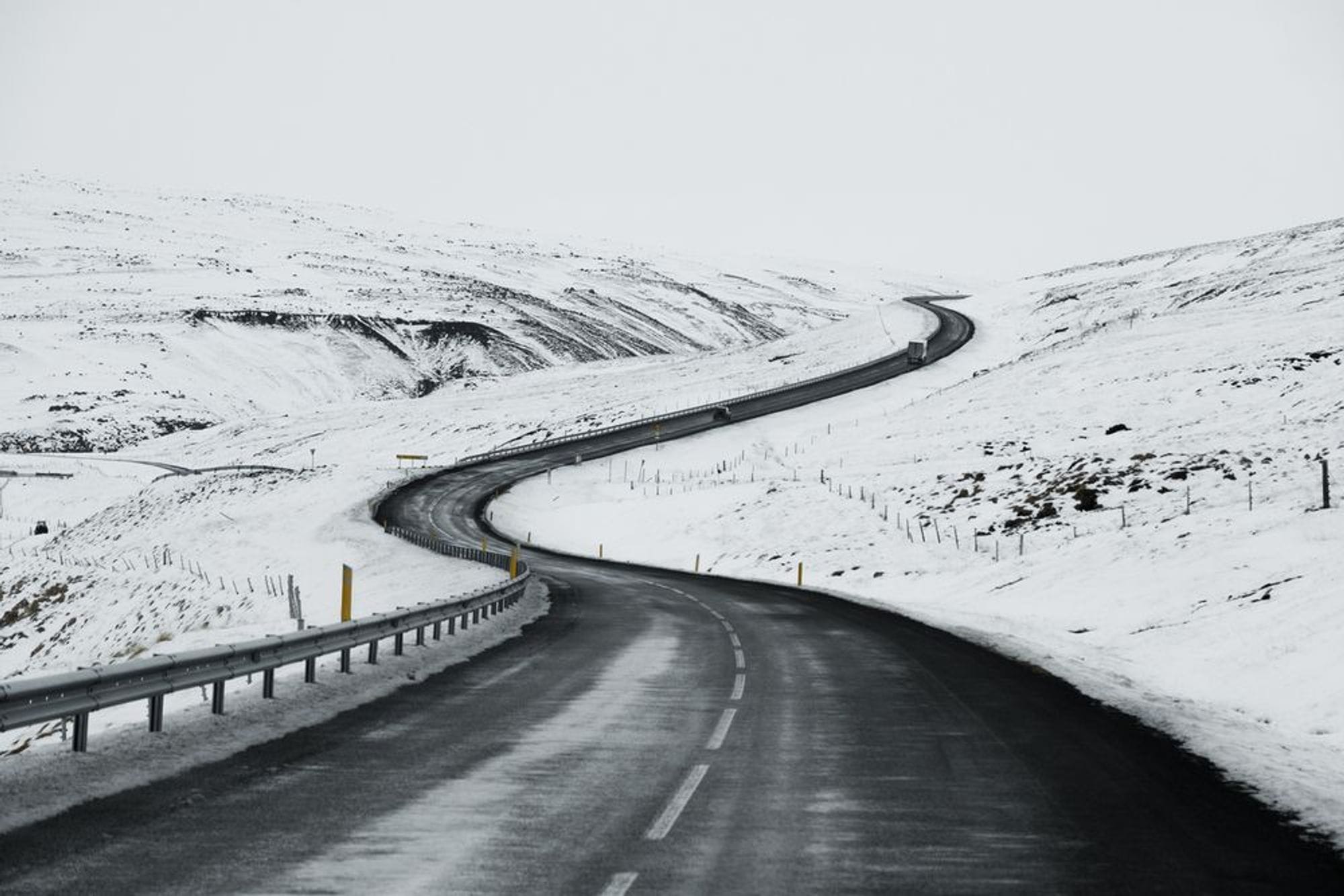 Snow banks by side of a road leading up a hill
