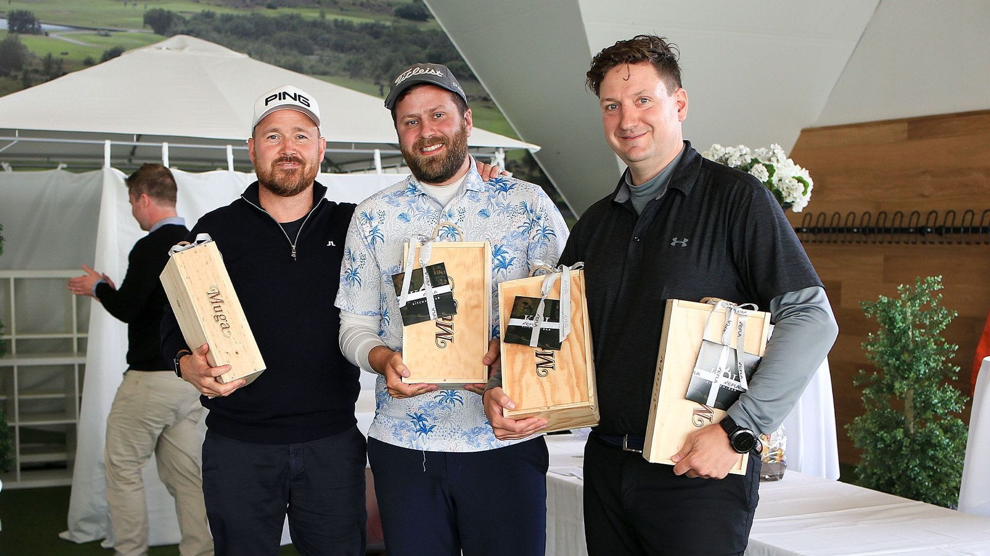Three men in casual outfits posing and holding wooden boxes 