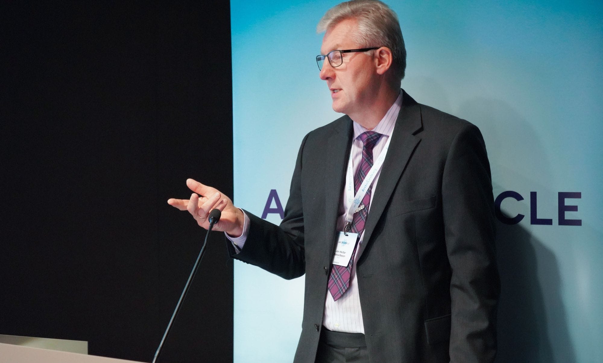 A man speaking into a microphone with hand gesture