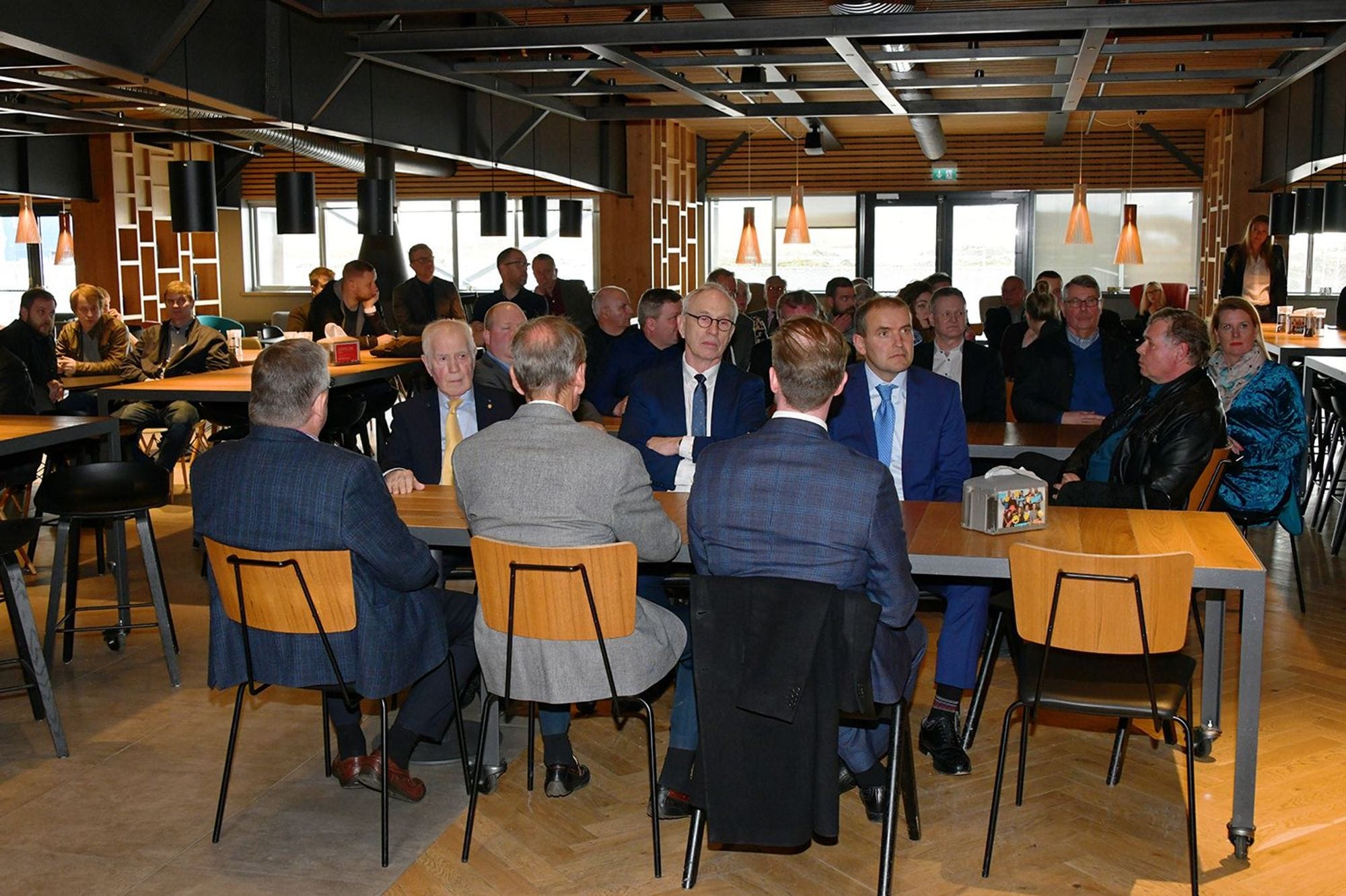 Group of business men seated inside a room with wooden interiors and large windows