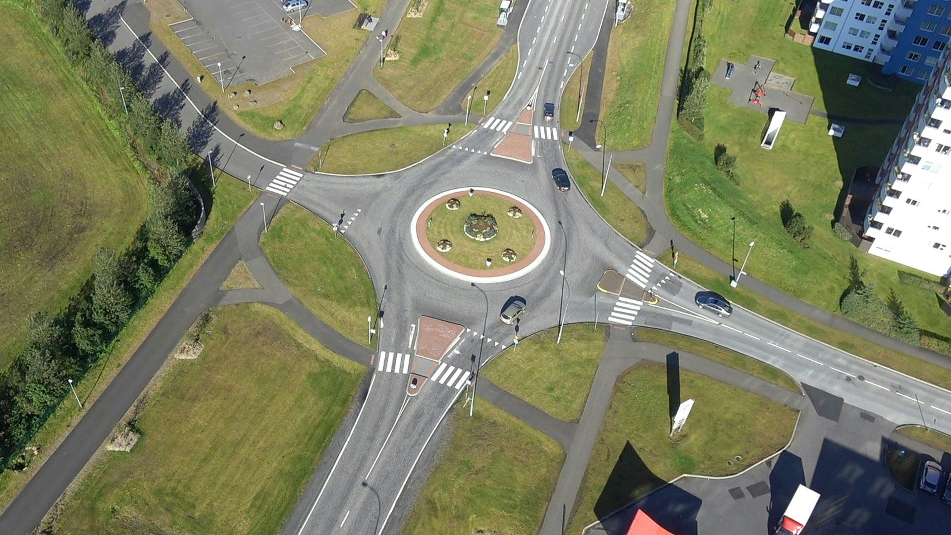 An aerial view of a roundabout with several exits and vehicles 