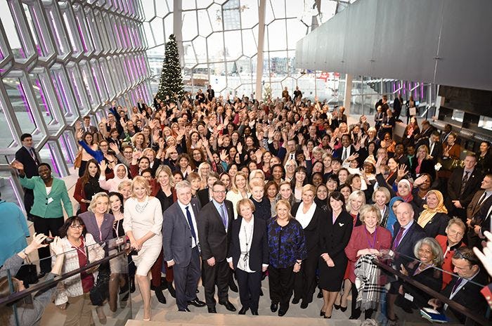A crowd mainly consist of women and few men standing together posing 