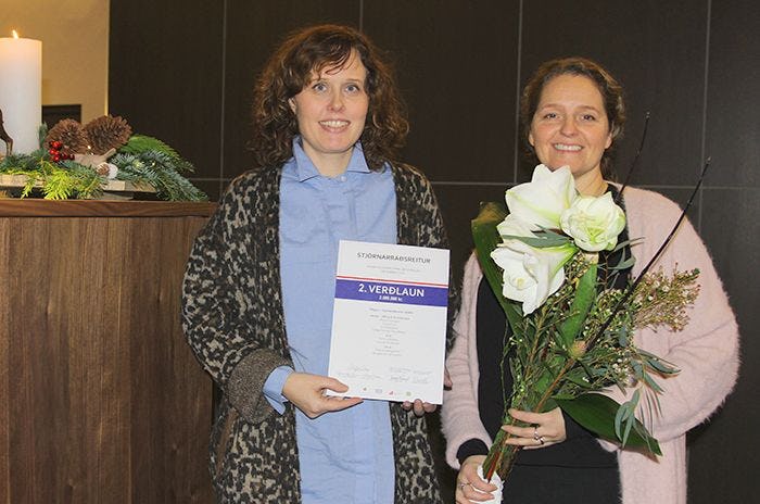 Two women holding bouquet of flower and certificate 