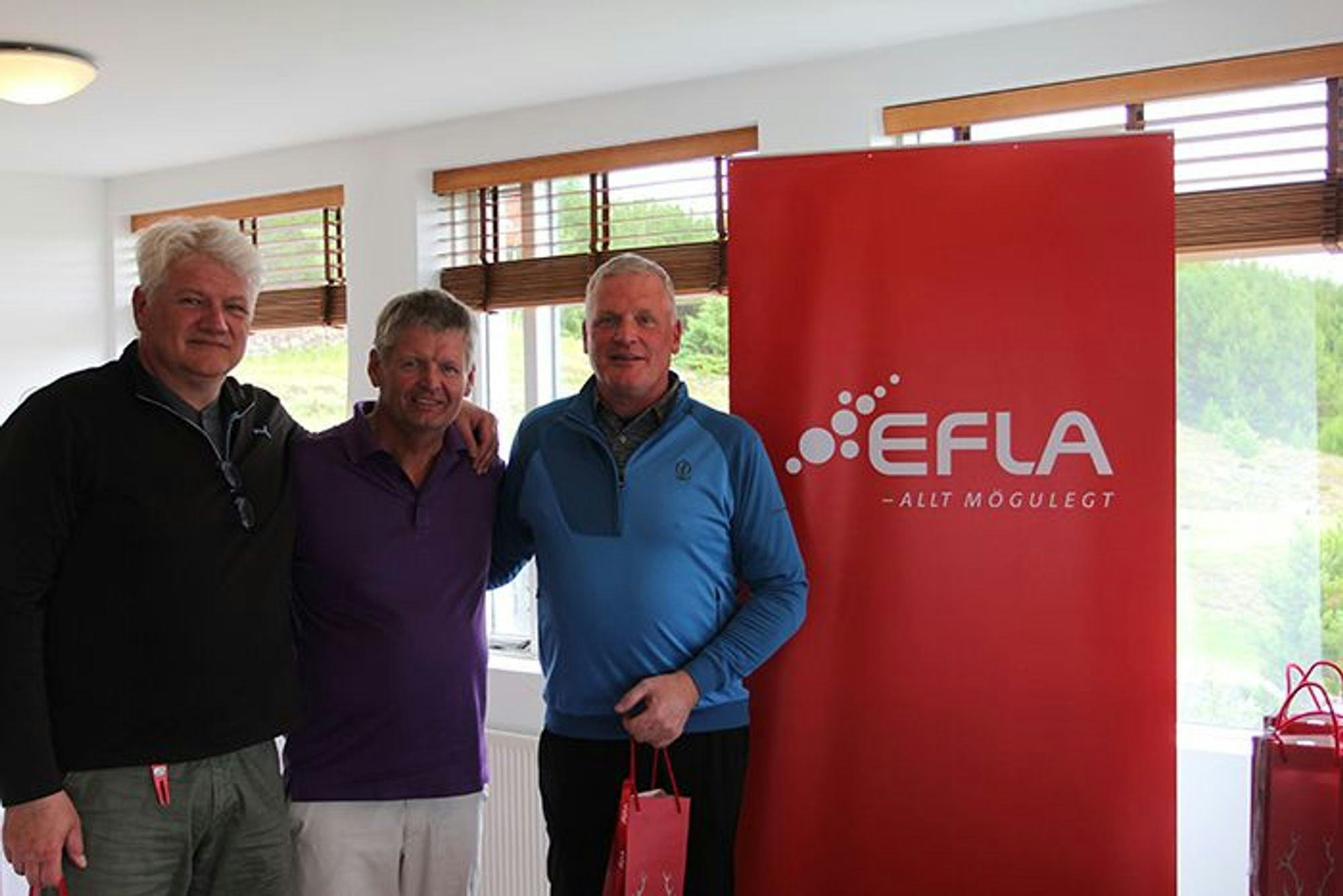 Three smiling men standing in front of a red EFLA promotional banner