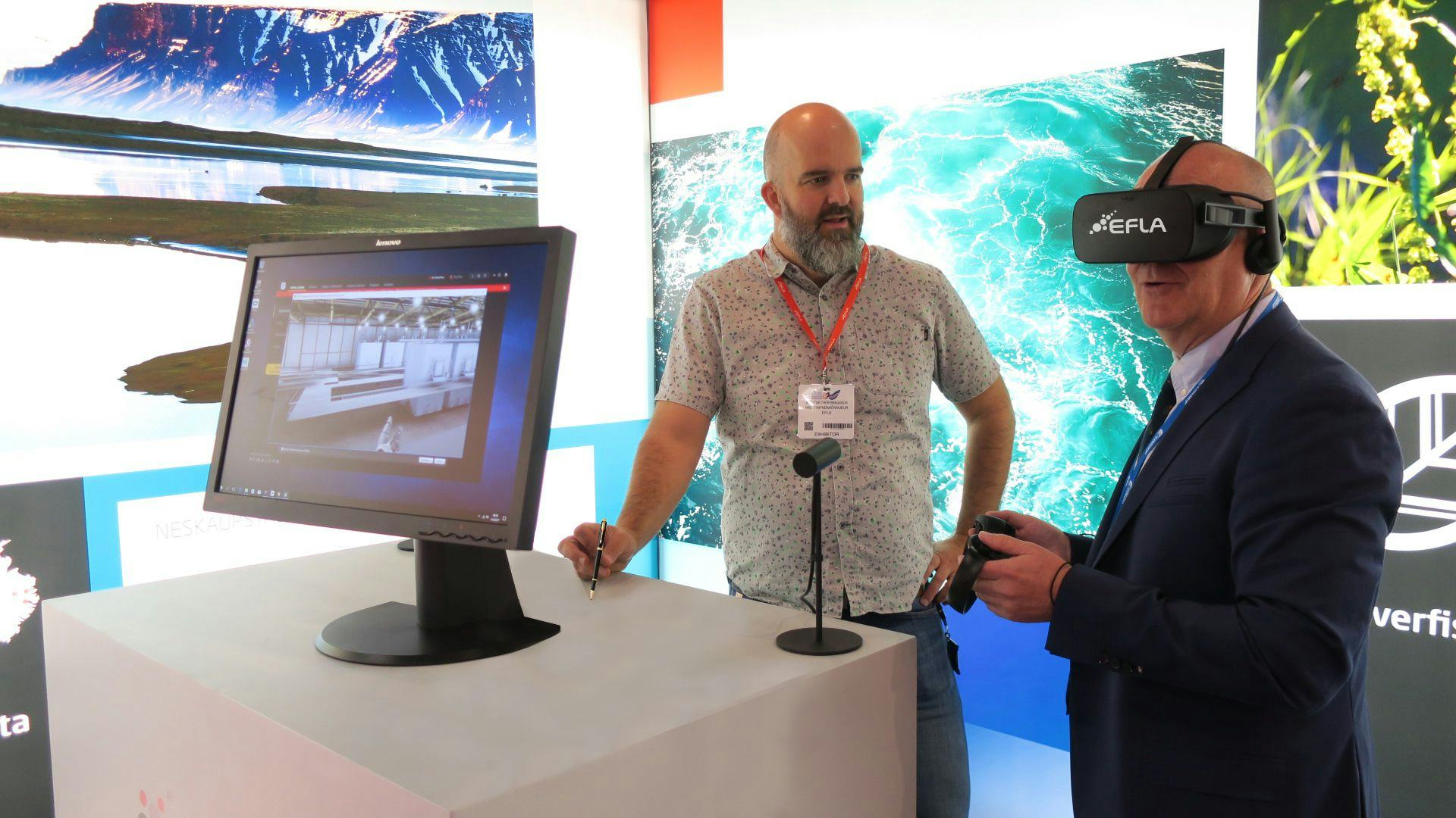 Two men at a exhibition, with one man demonstrating a VR set