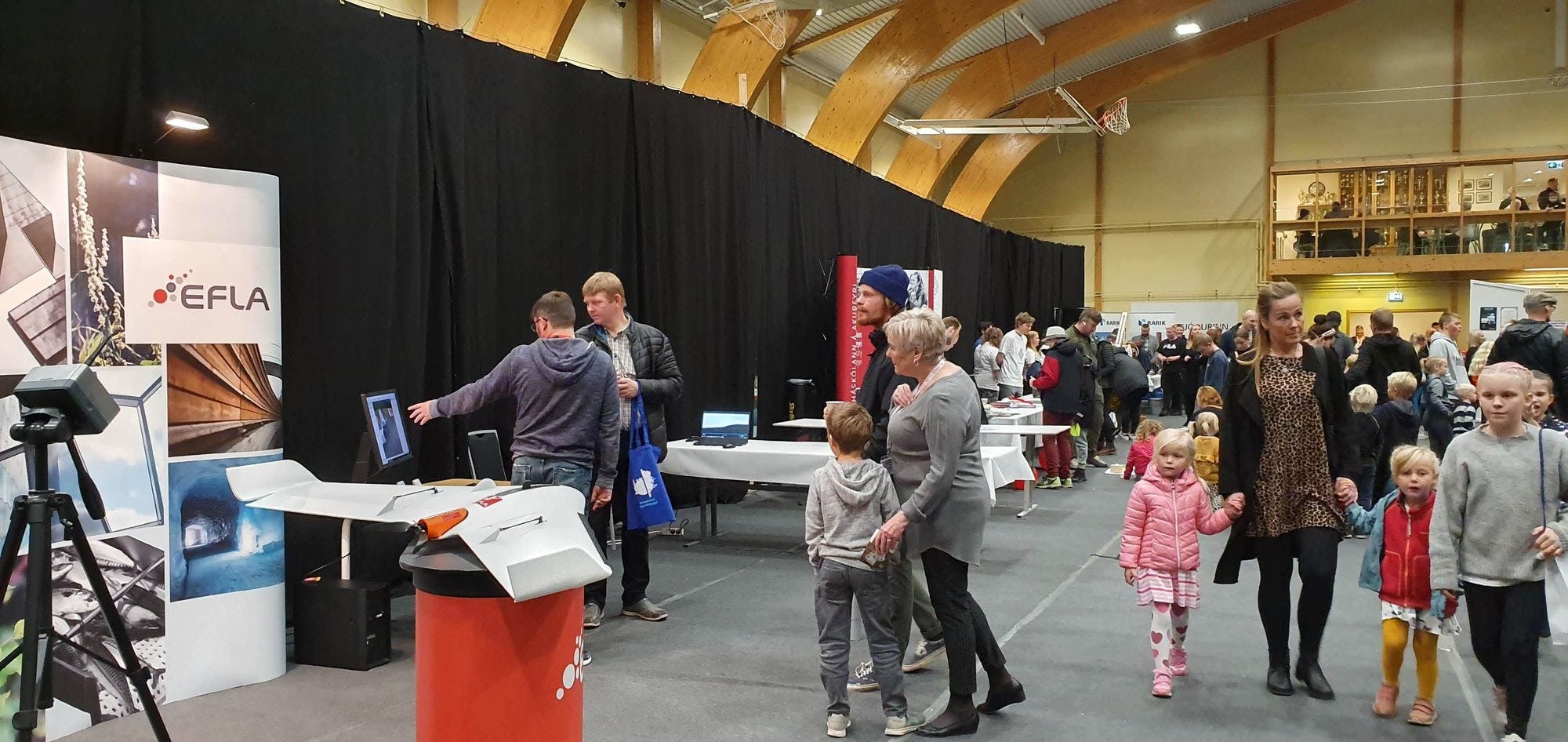 An indoor event where people are engaging with exhibition booth about drones