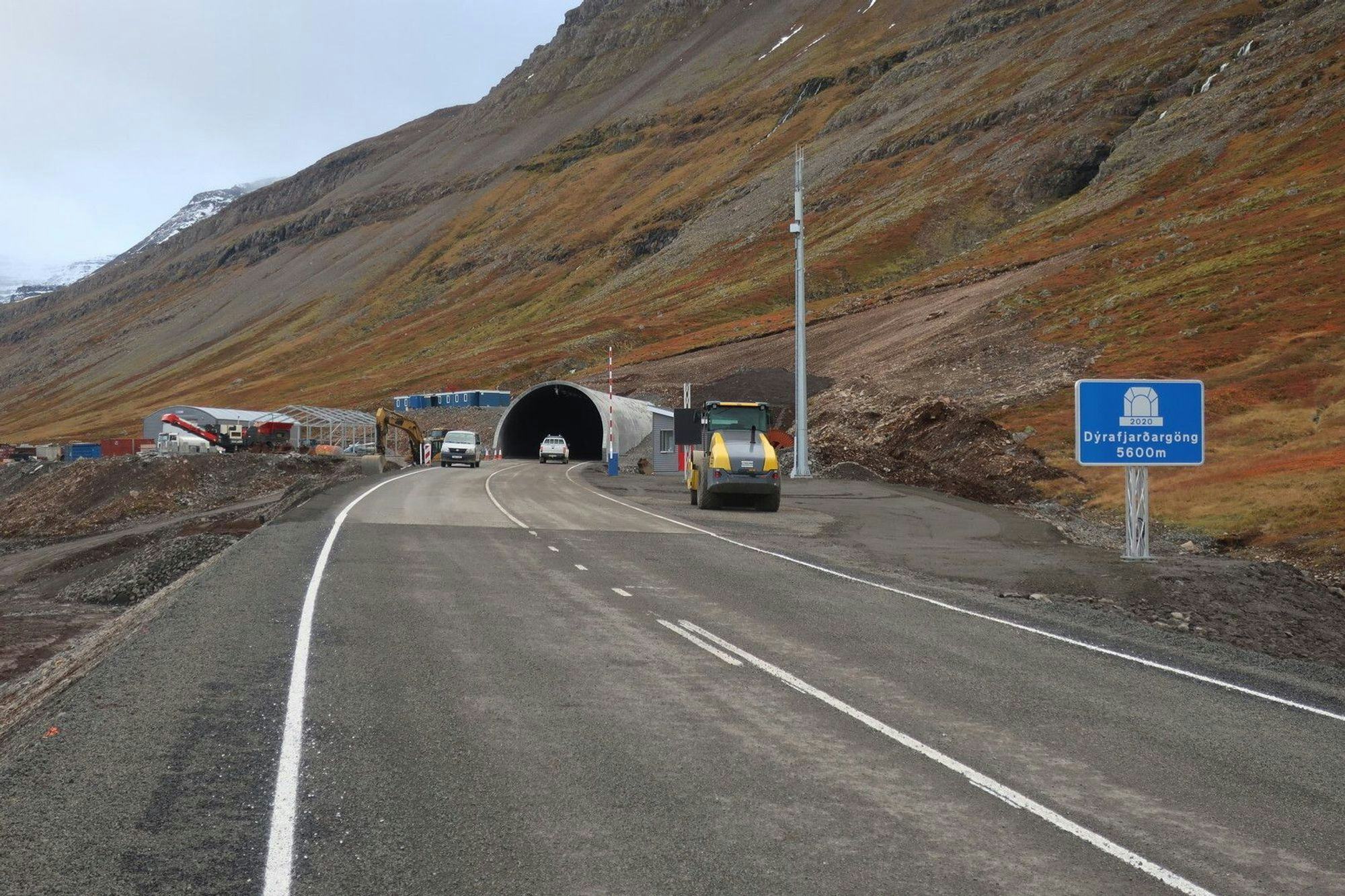 A road leading to a tunnel entrance with construction work set against a mountainous landscape
