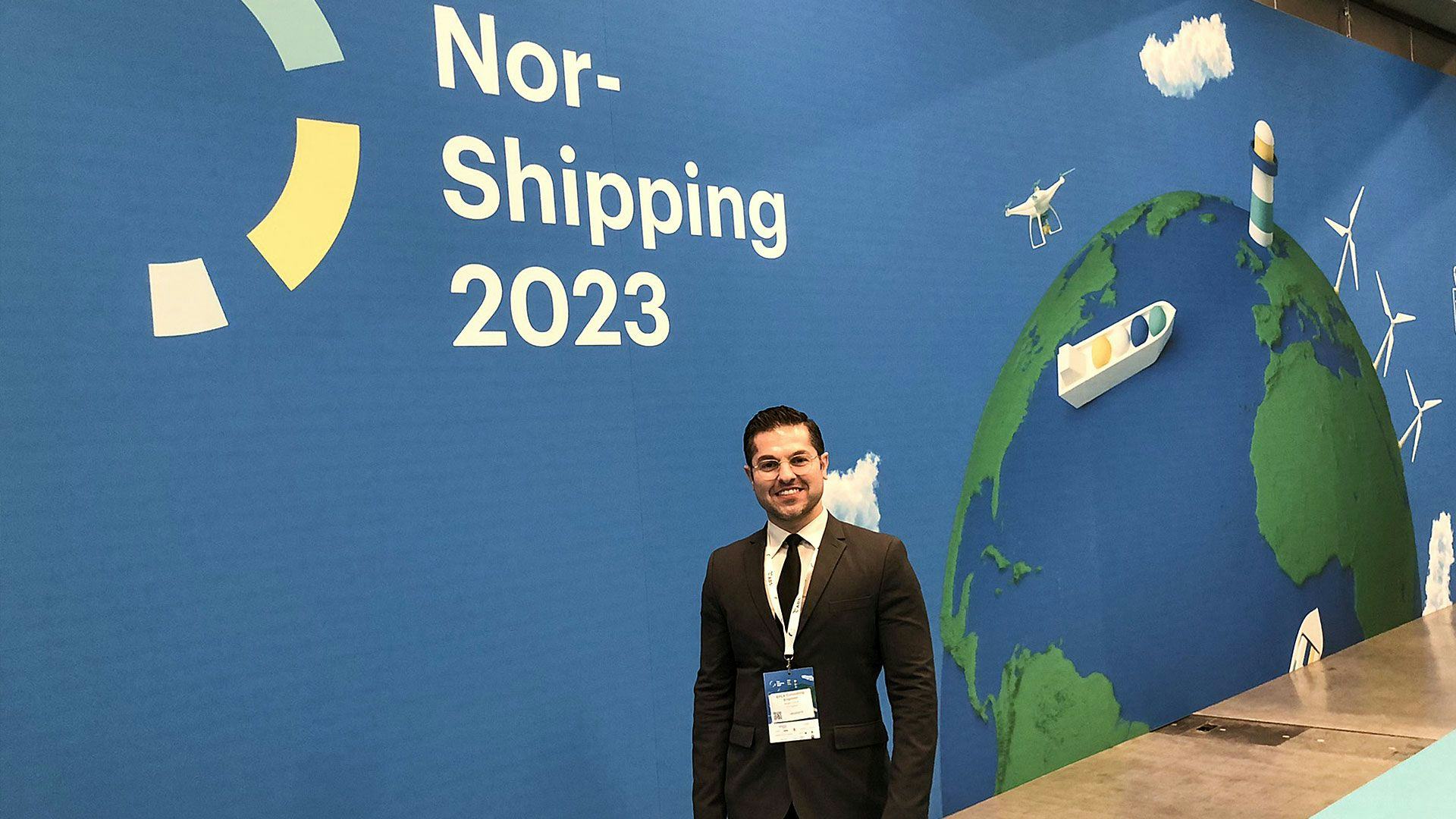 A man standing in front of a backdrop featuring graphics of globe, a drone and a ship