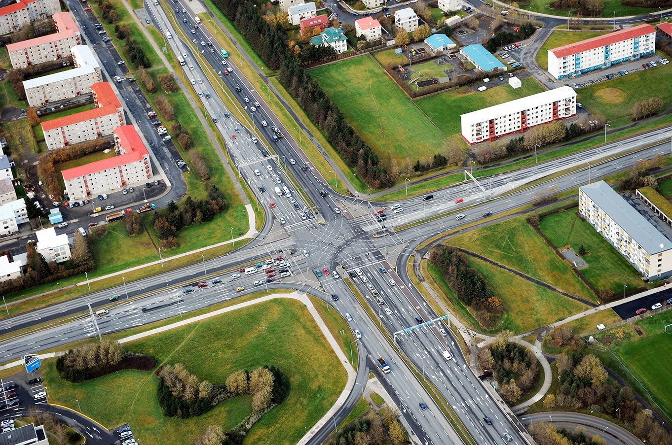 A complex intersection with multiple roadways, pedestrian paths and surrounding buildings