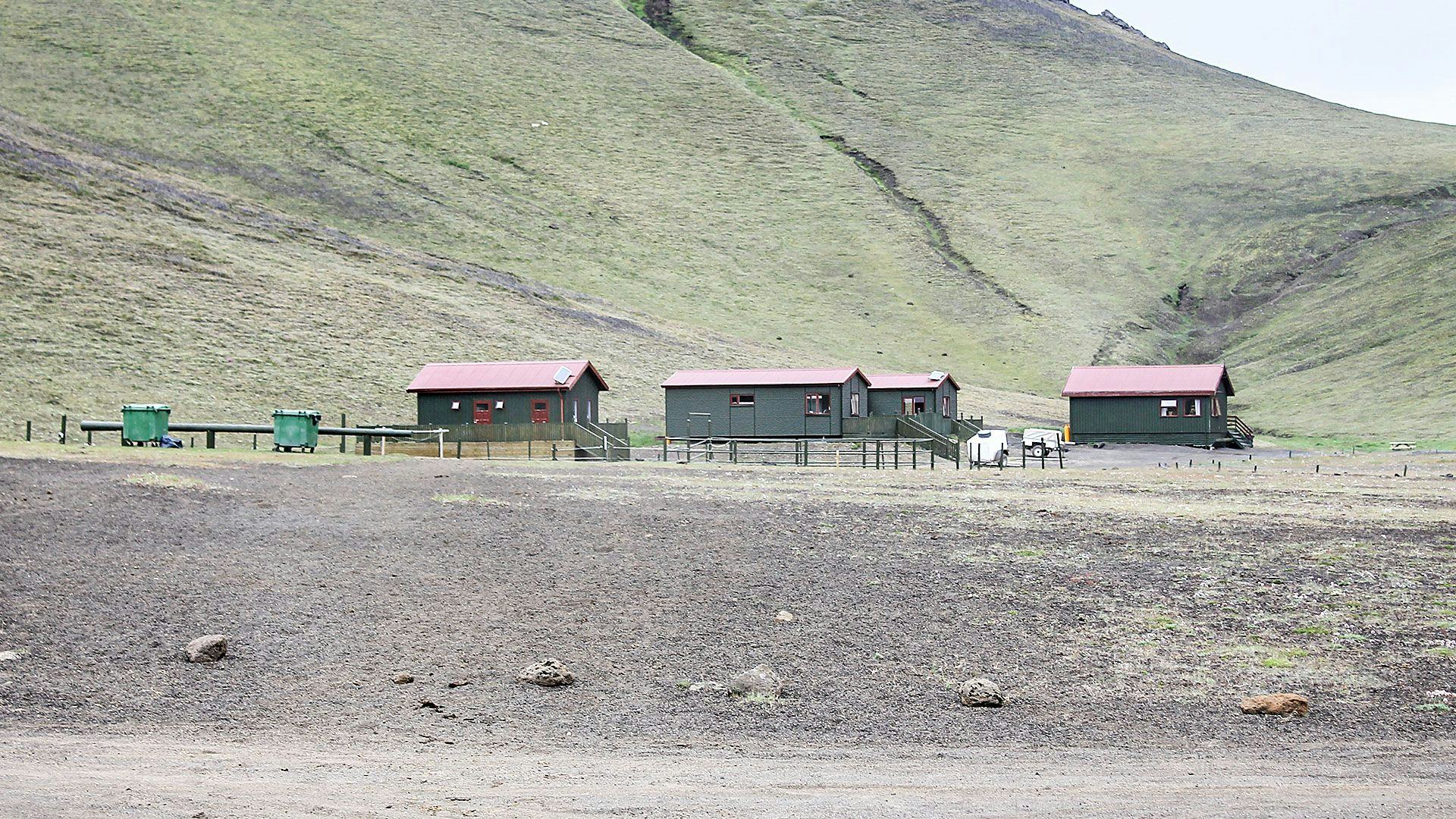 A rural landscape featuring three small structured cabins or shelters