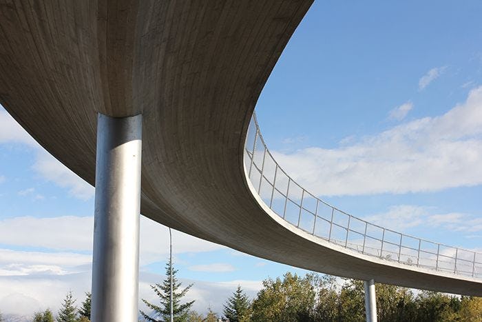 An image of curved pedestrian bridge from bottom, with clear sky in the background