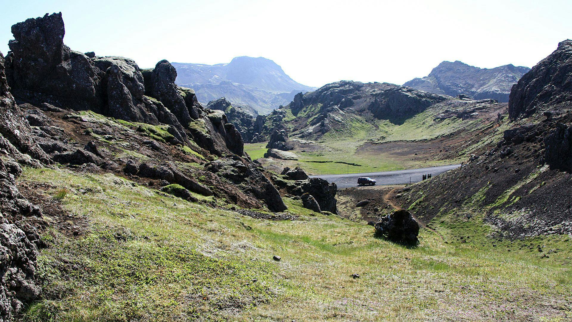 A rugged landscape with grassy area and dark rocky formation