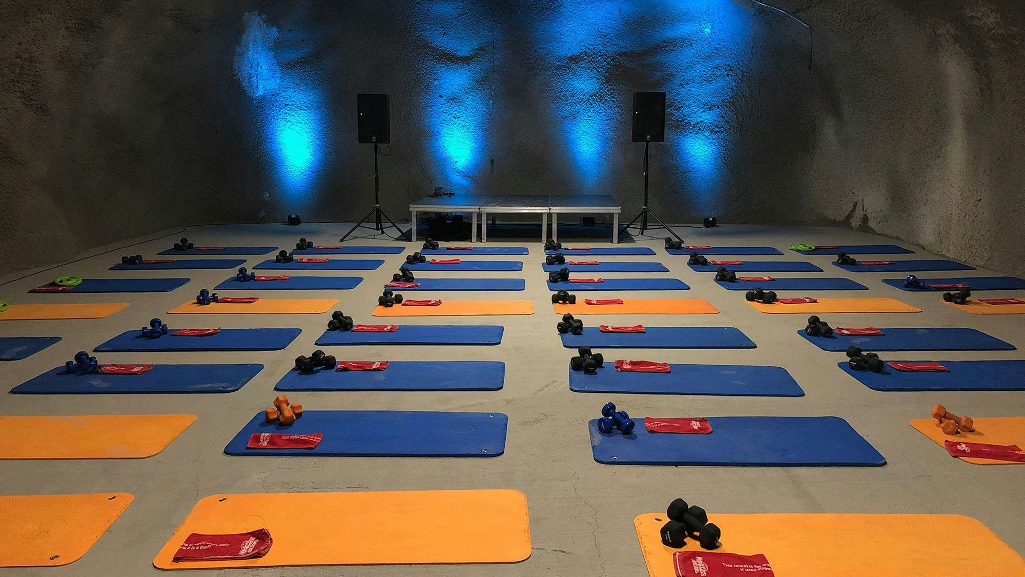 blue and yellow yoga mats arranged in a large room with blue lightings