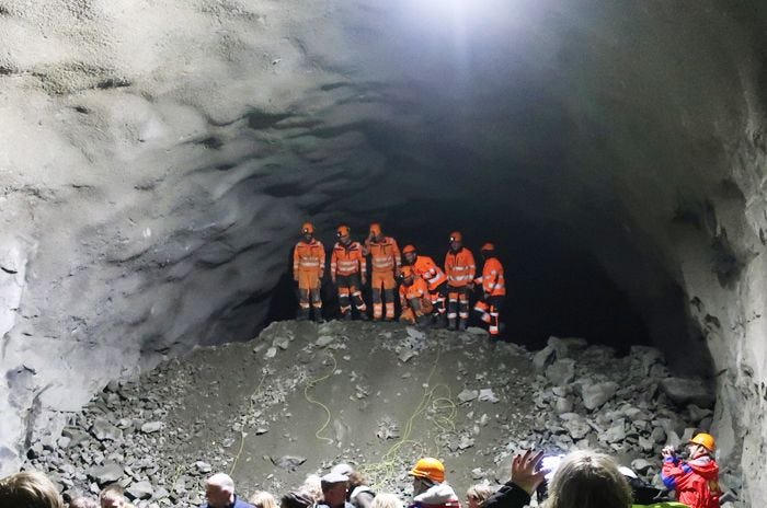 A work crew gathered in a large rocky cave or tunnel entrance