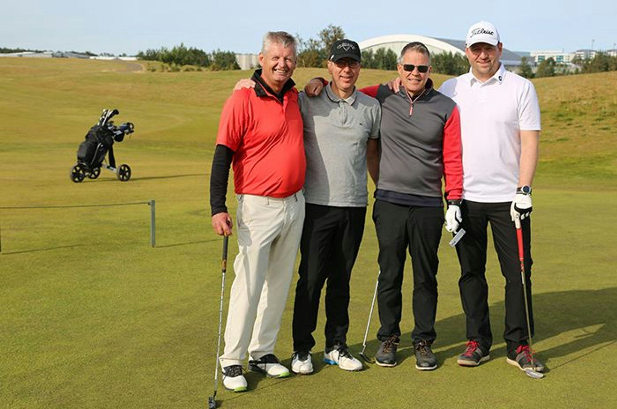 Four men posing on a golf course