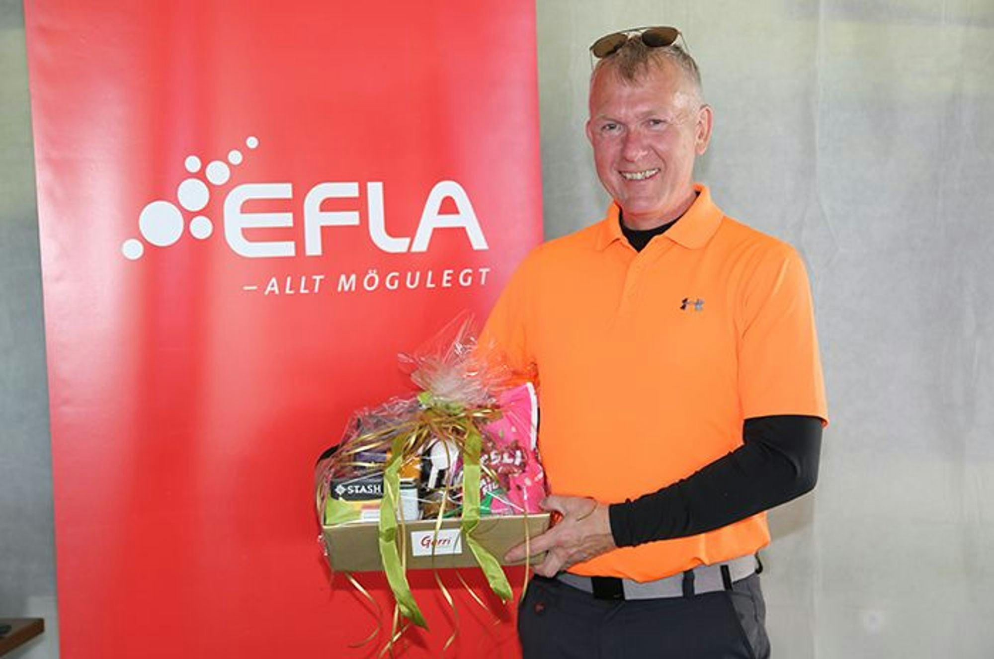 A man holding gift basket and  standing next to EFLA red promotional banner