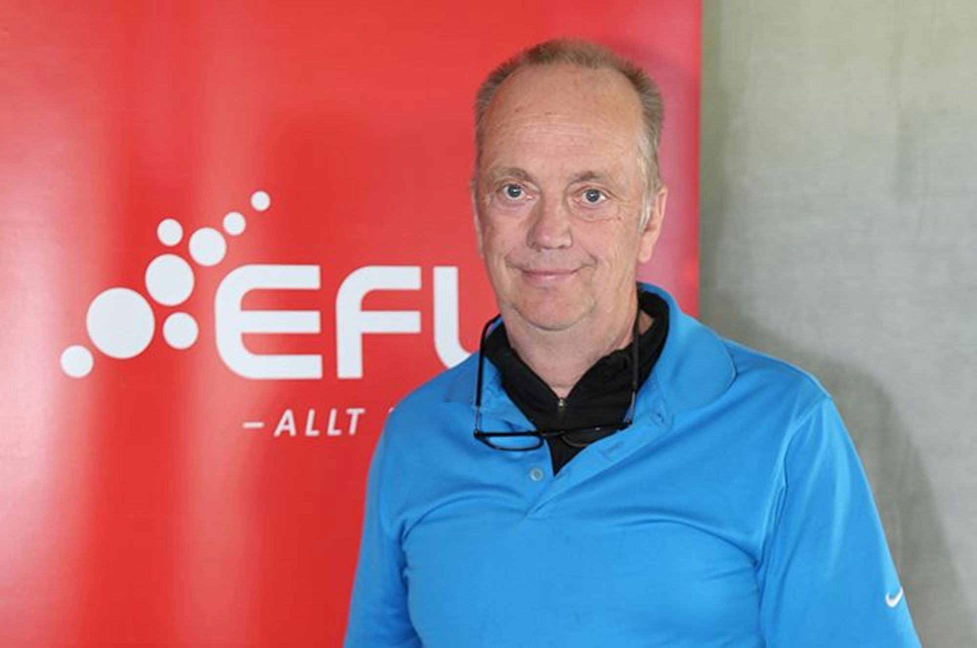 A man standing next to EFLA red promotional banner