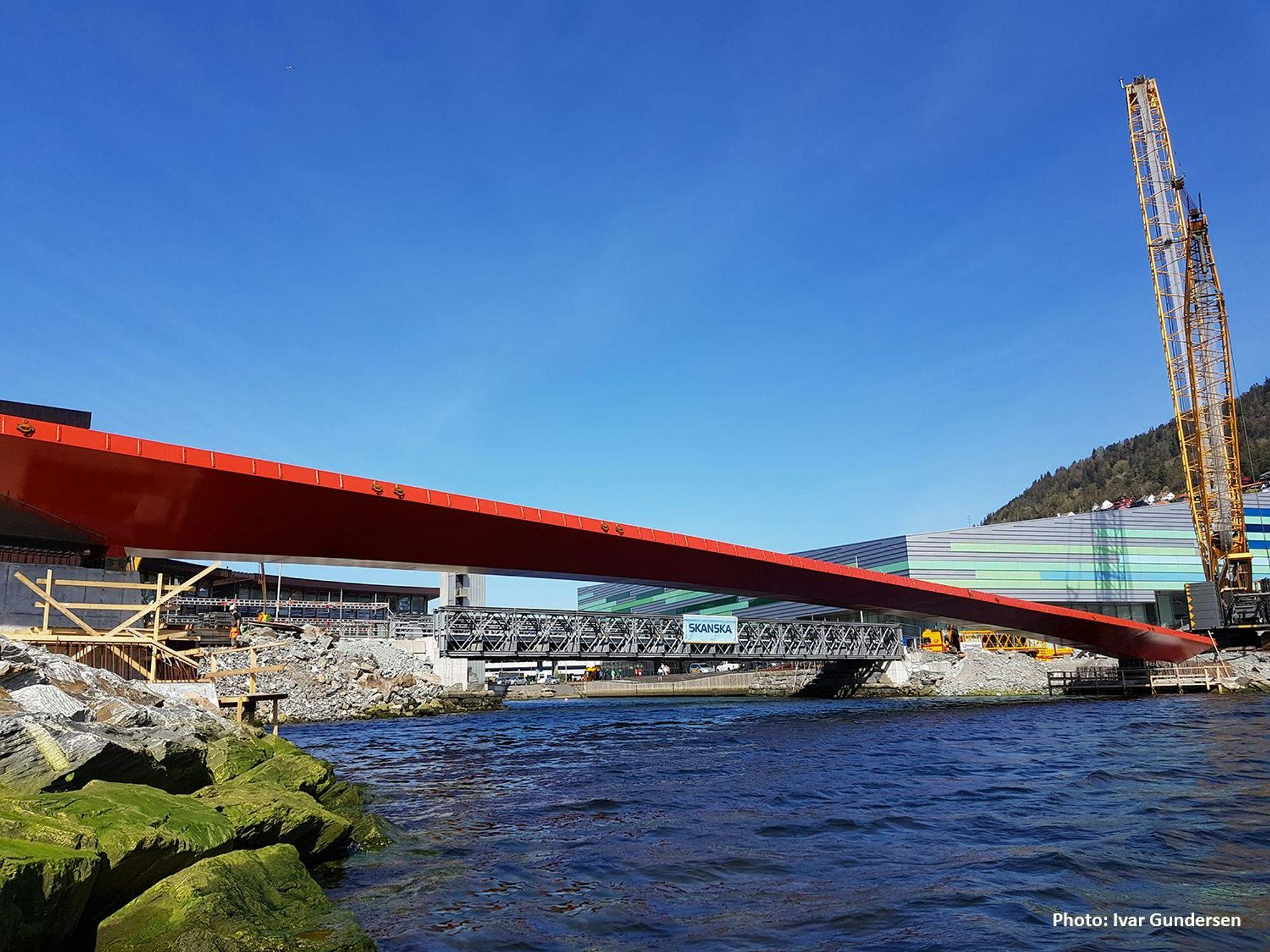 A red pedestrian bridge under construction and a clear clear blue sky at the background