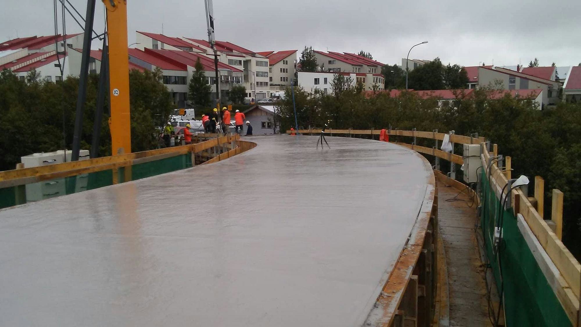 Newly cast concrete surface of a bridge with construction workers in the background