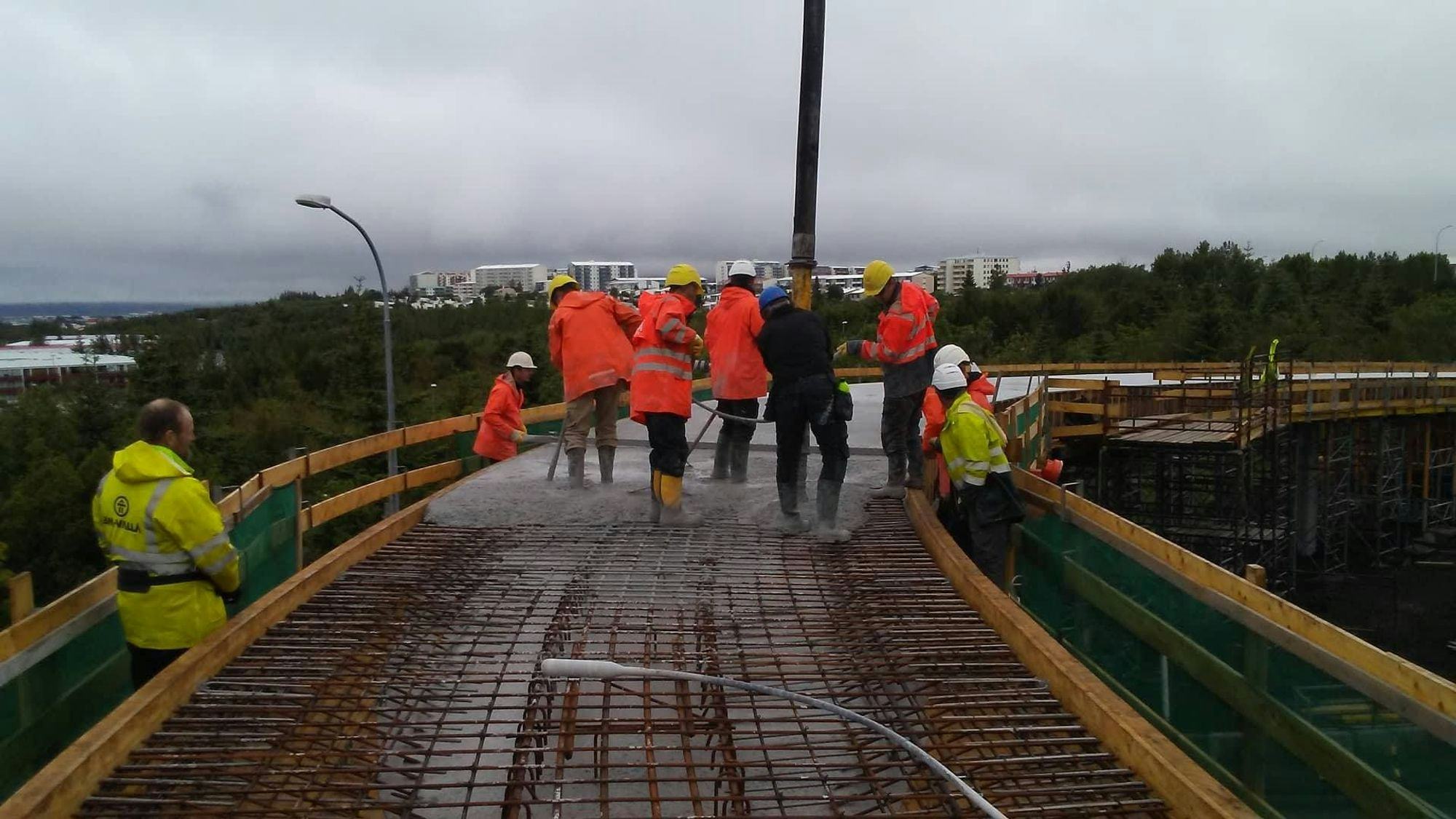 Group of construction workers walking on a bridge with exposed rebar