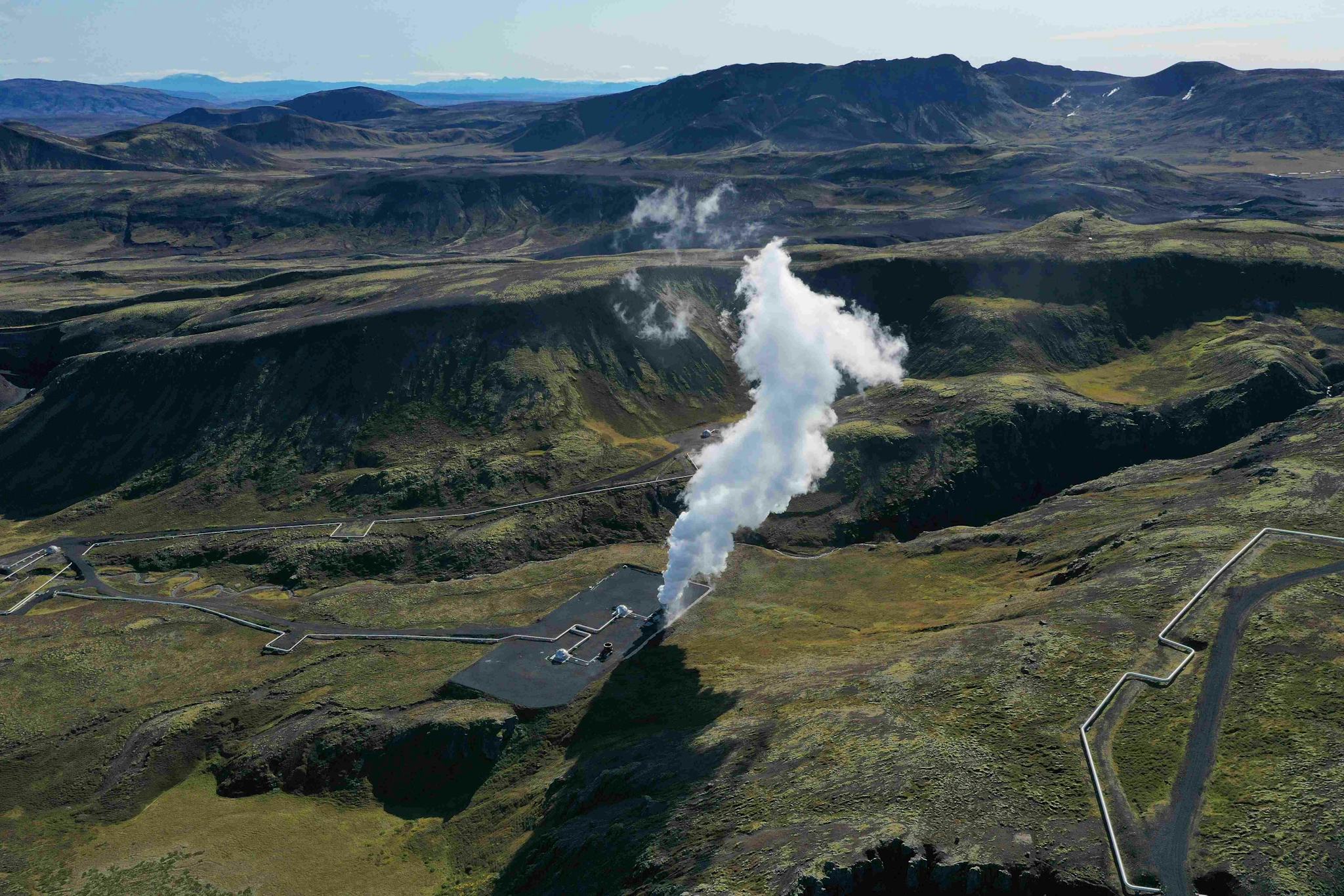 A geothermal area with steam rising from the ground