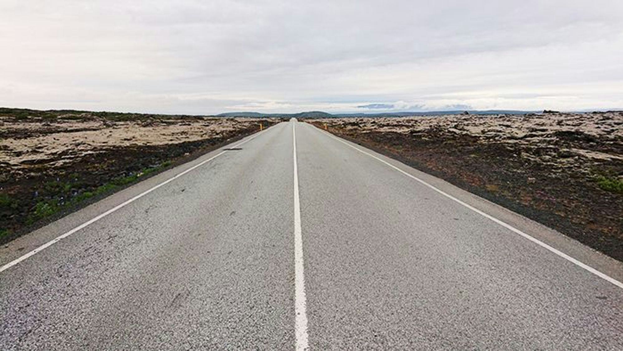 A straight empty road stretched into the distance through a barren landscape