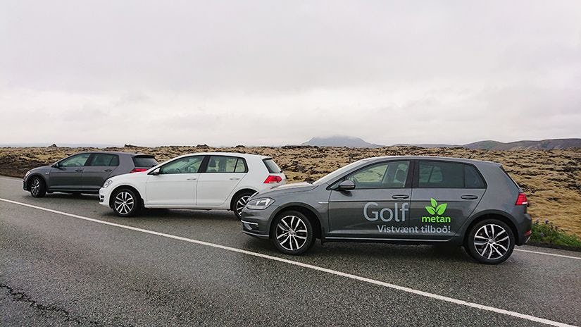 A line up of cars on a road with a barren landscape in the background