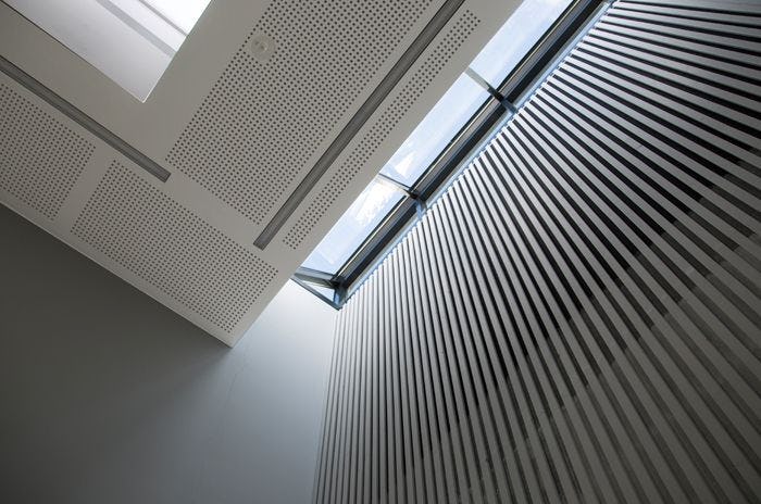 An interior of a building with windows letting in sunlight and geometric pattern ceiling