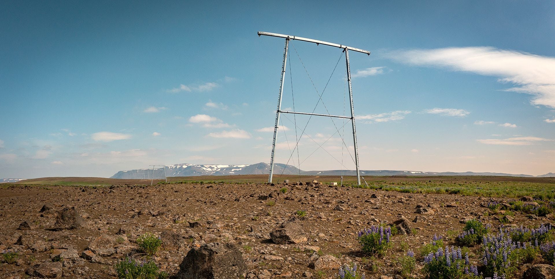 A large metallic structure, possibly power line with a mountain in the background