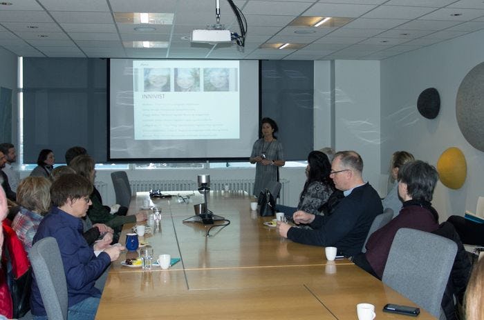 A woman giving presentation to a group of people in a room