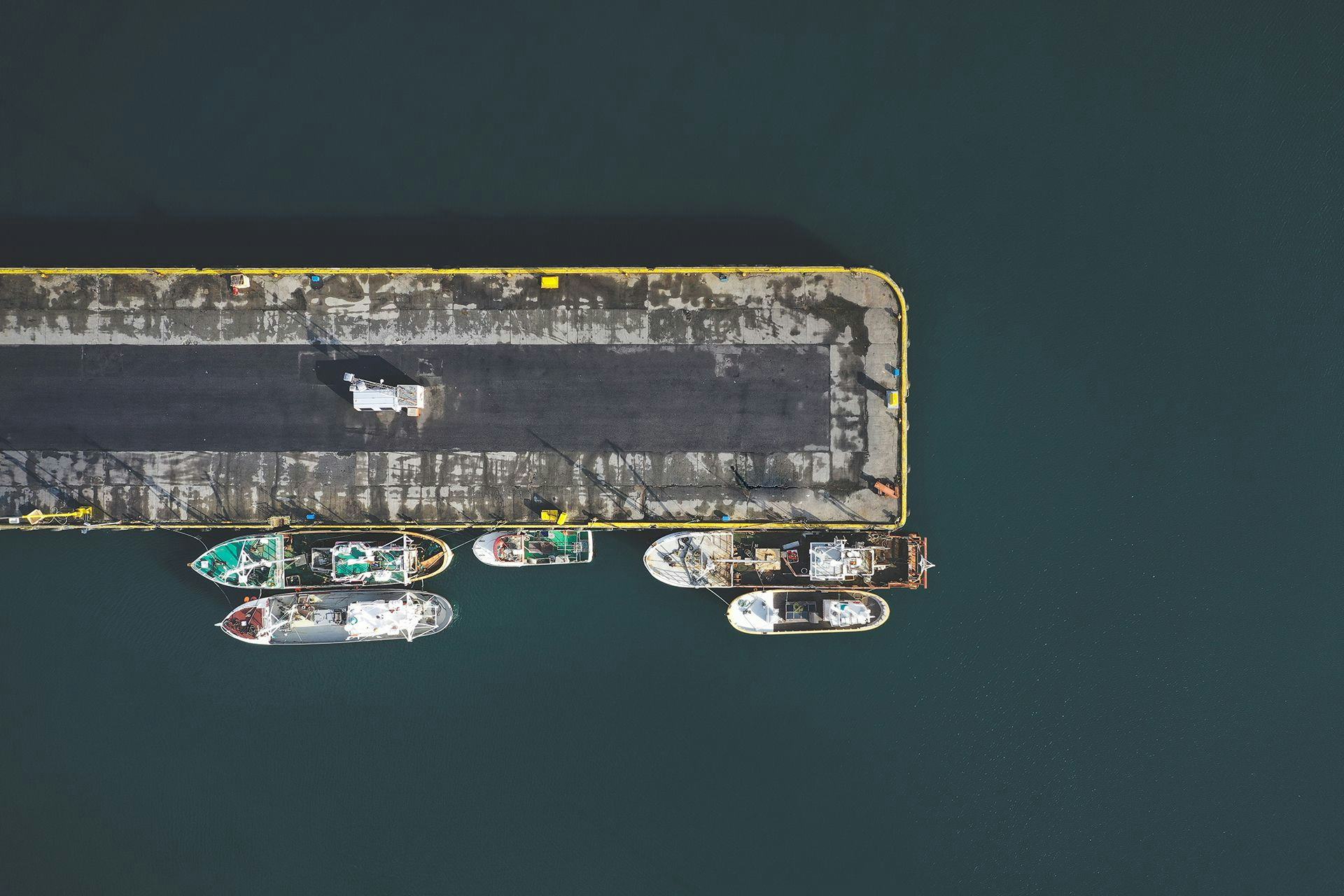 An aerial view of boats docked alongside a pier in a harbor