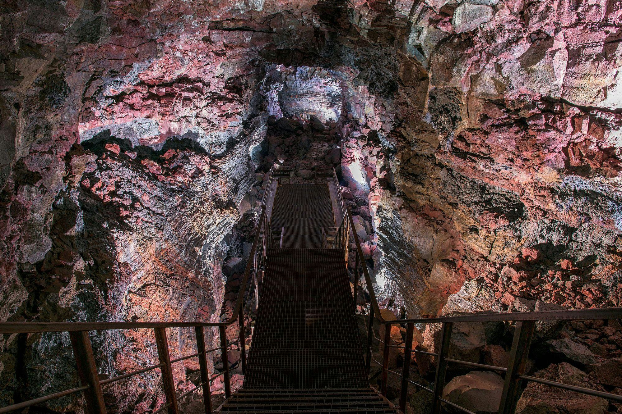 metal stairs leading towards red stone wall in a cave