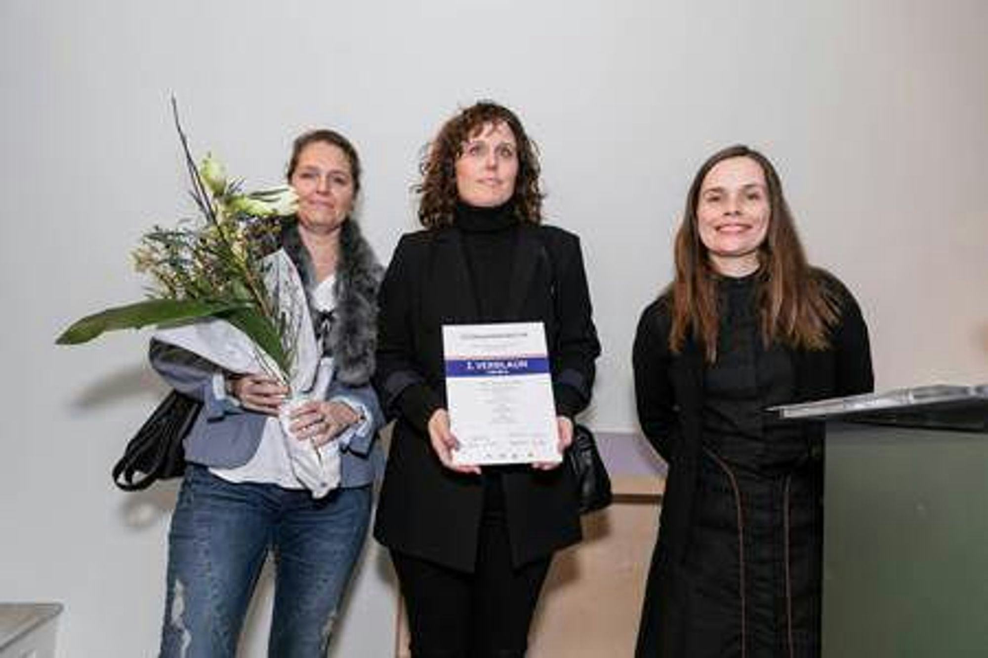 Three women holding flower bouquet and certificate