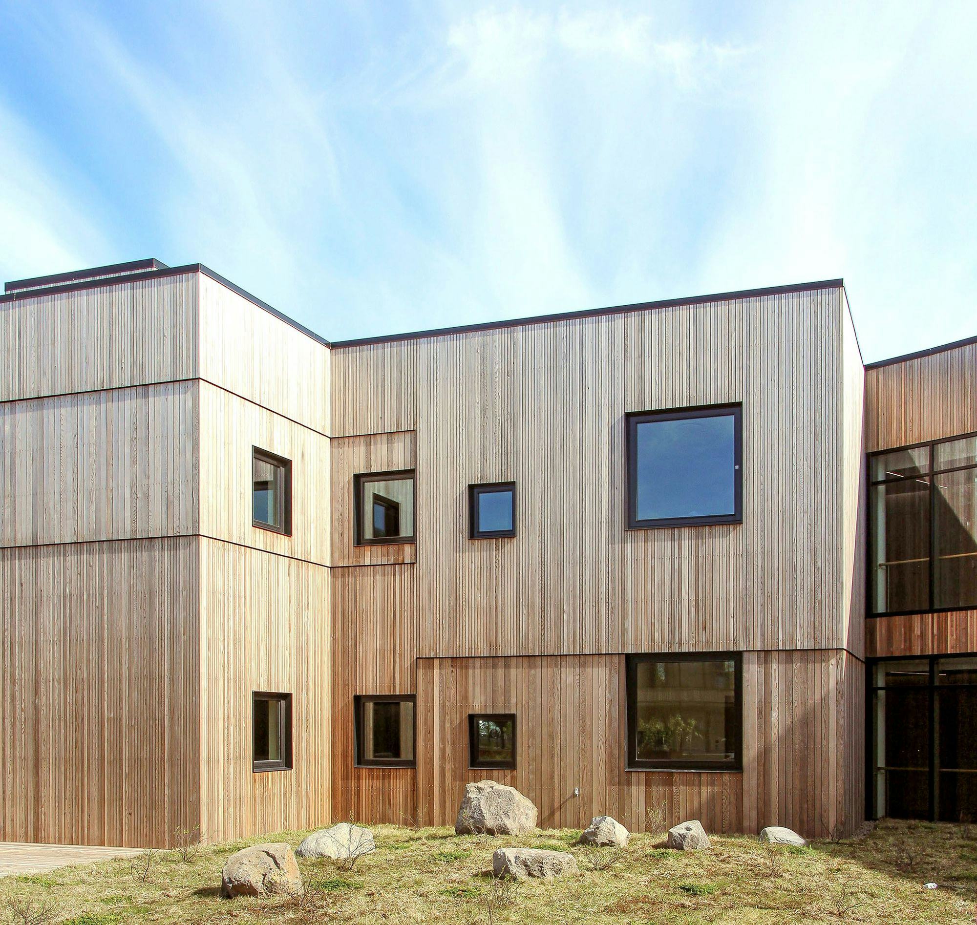 A wooden clad building with various sized windows