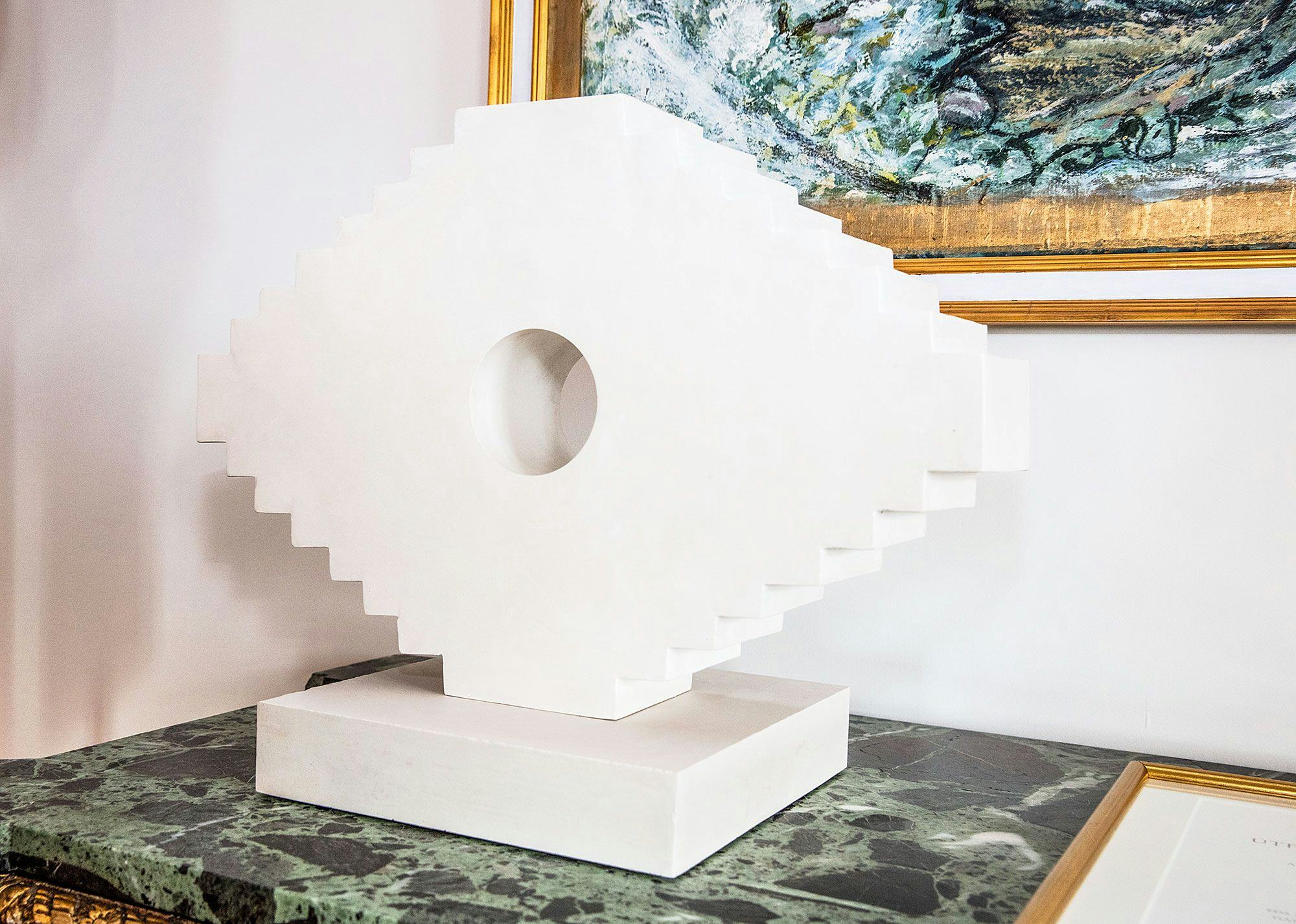 A white sculpture with geometric design on a marble base