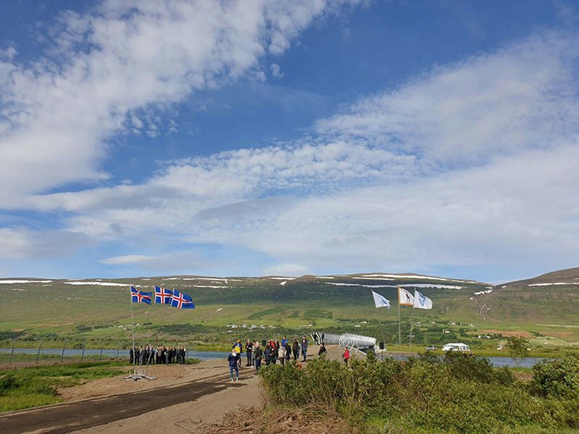 A group of people carrying flags, gathered in a scenic landscape