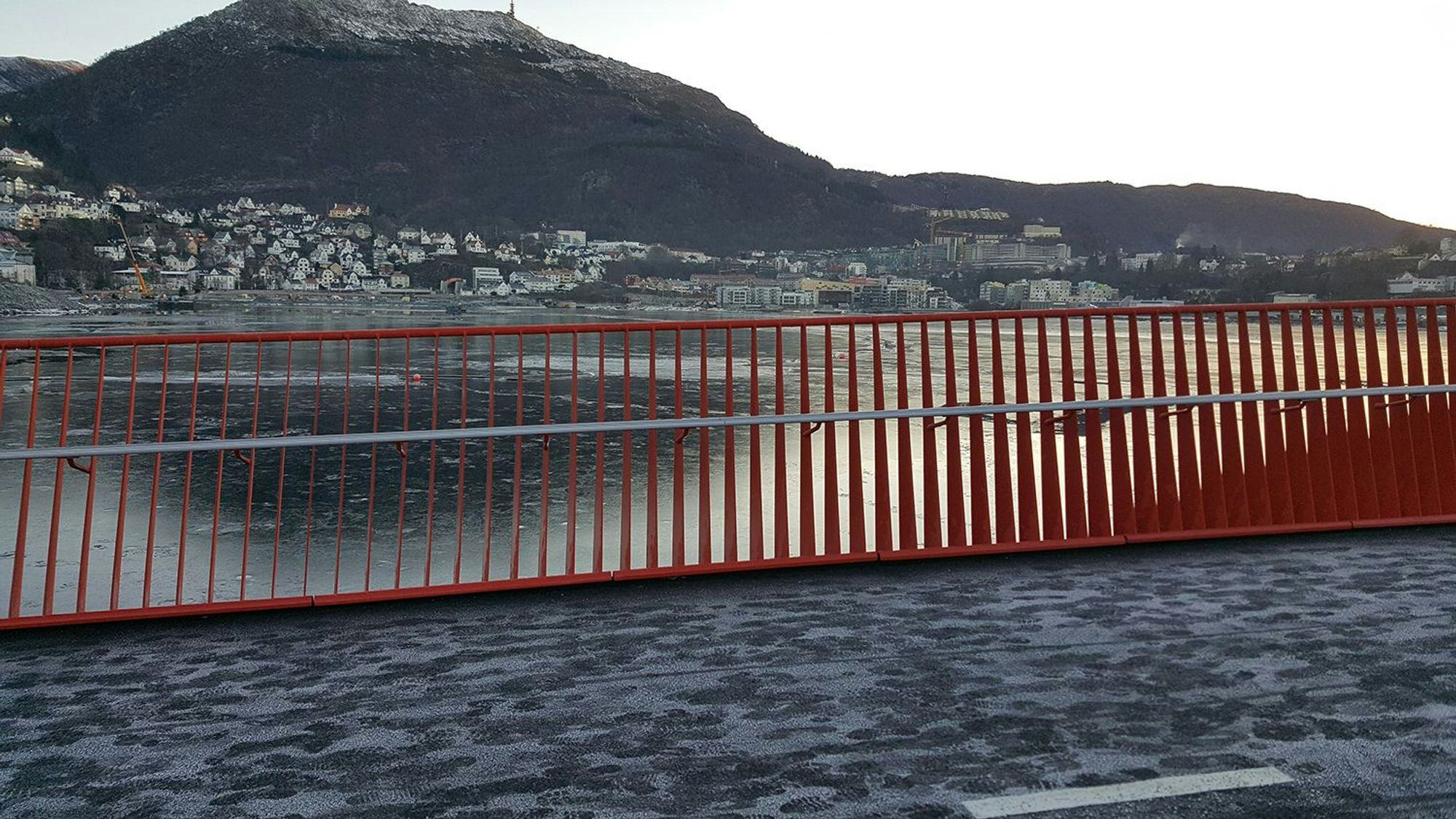 A red bridge over water with a mountain in the background