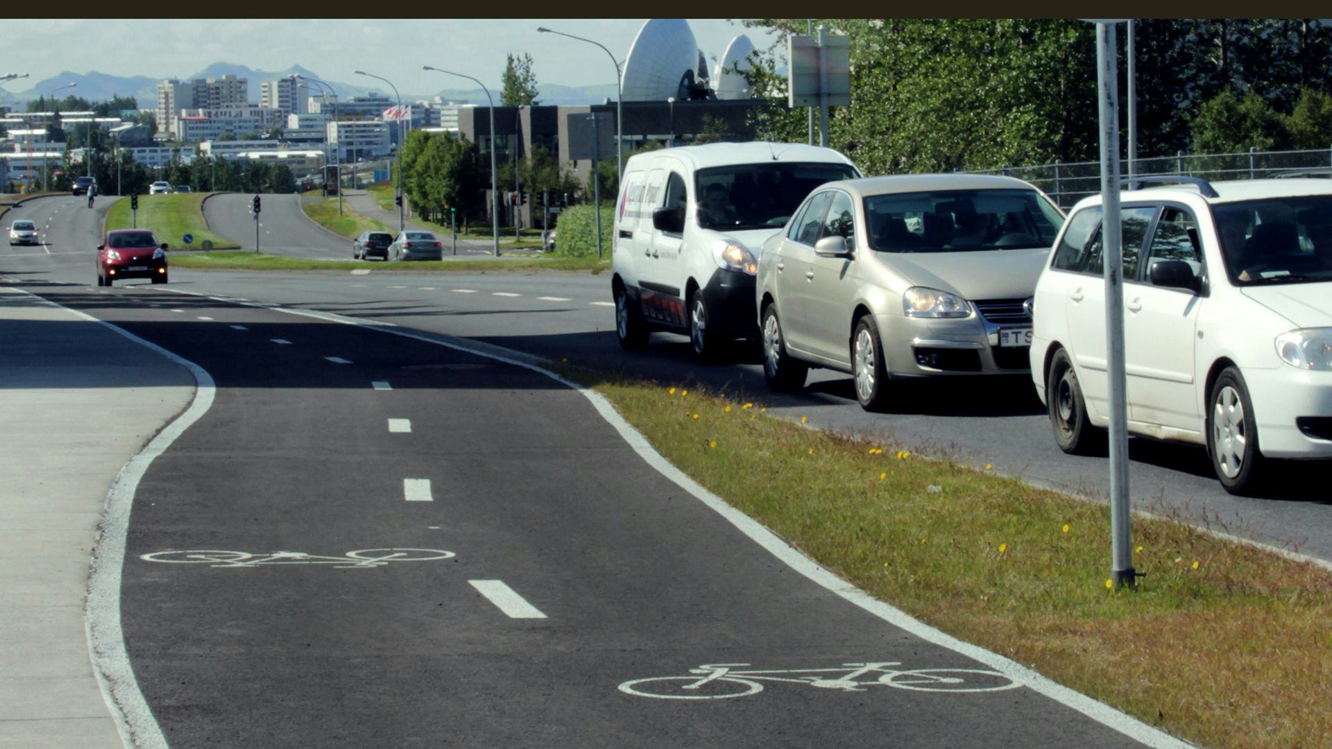 An urban scene with bicycle lane and cars parked alongside