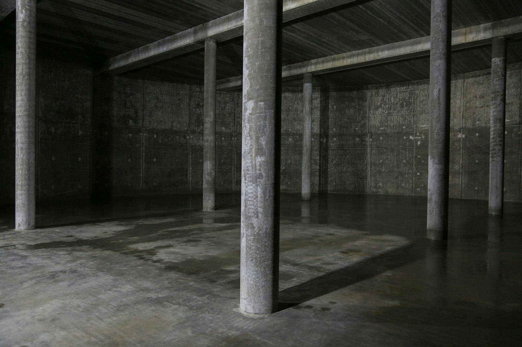 A dimly lit concrete space with pillars