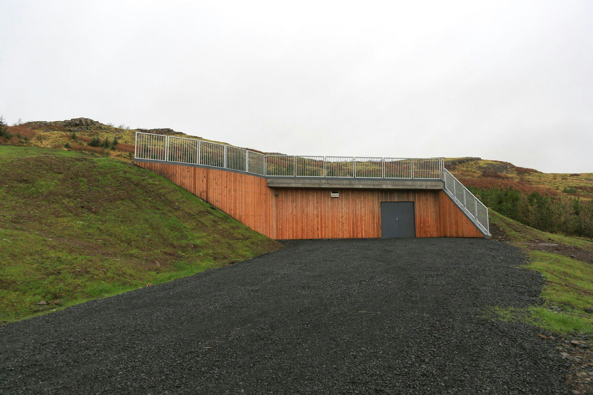 A modern structure with a wood facade built into a grassy hillside