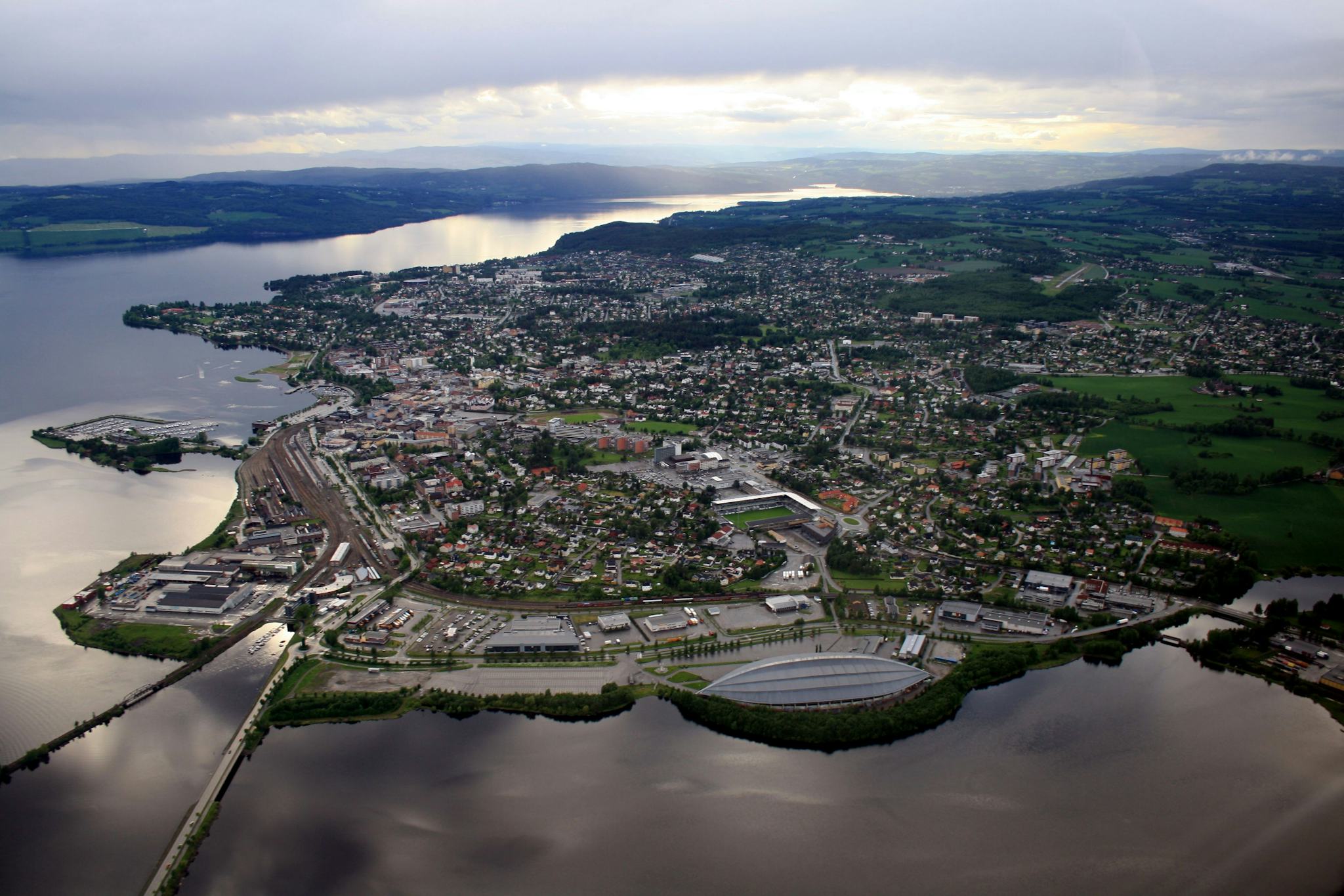 An aerial view of a coastal town with dense buildings and stadium near the water's edge
