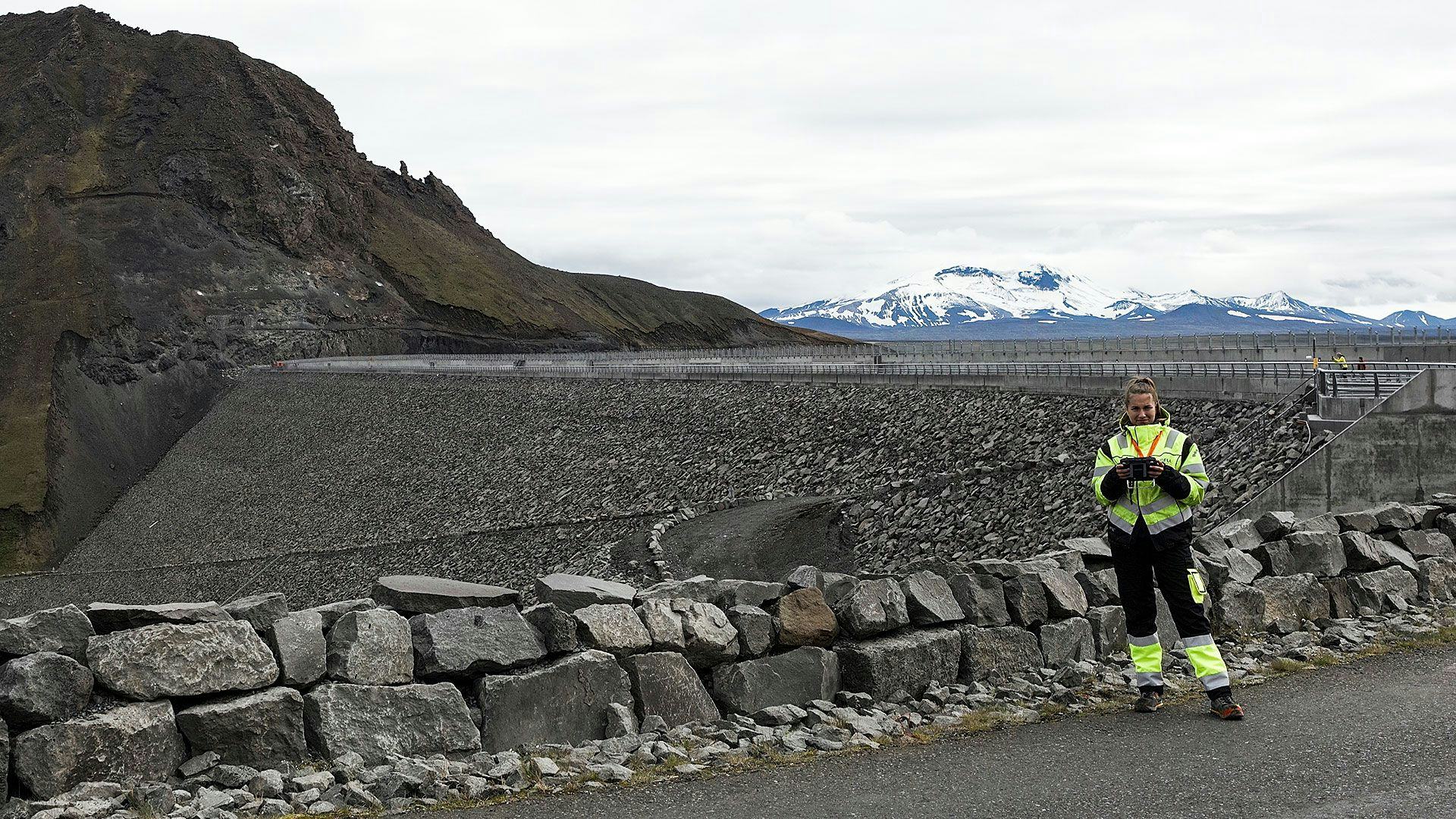 An individual in high visibility work wear standing in front of a rocky landscape 