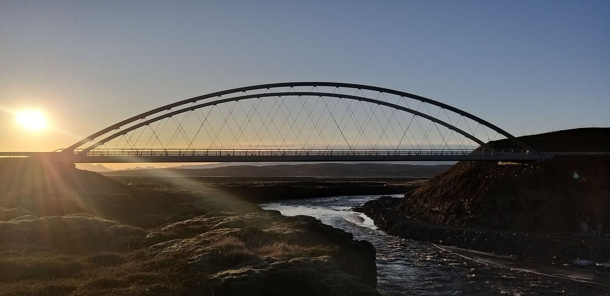 An arched bridge spanning across a river, captured at sunset