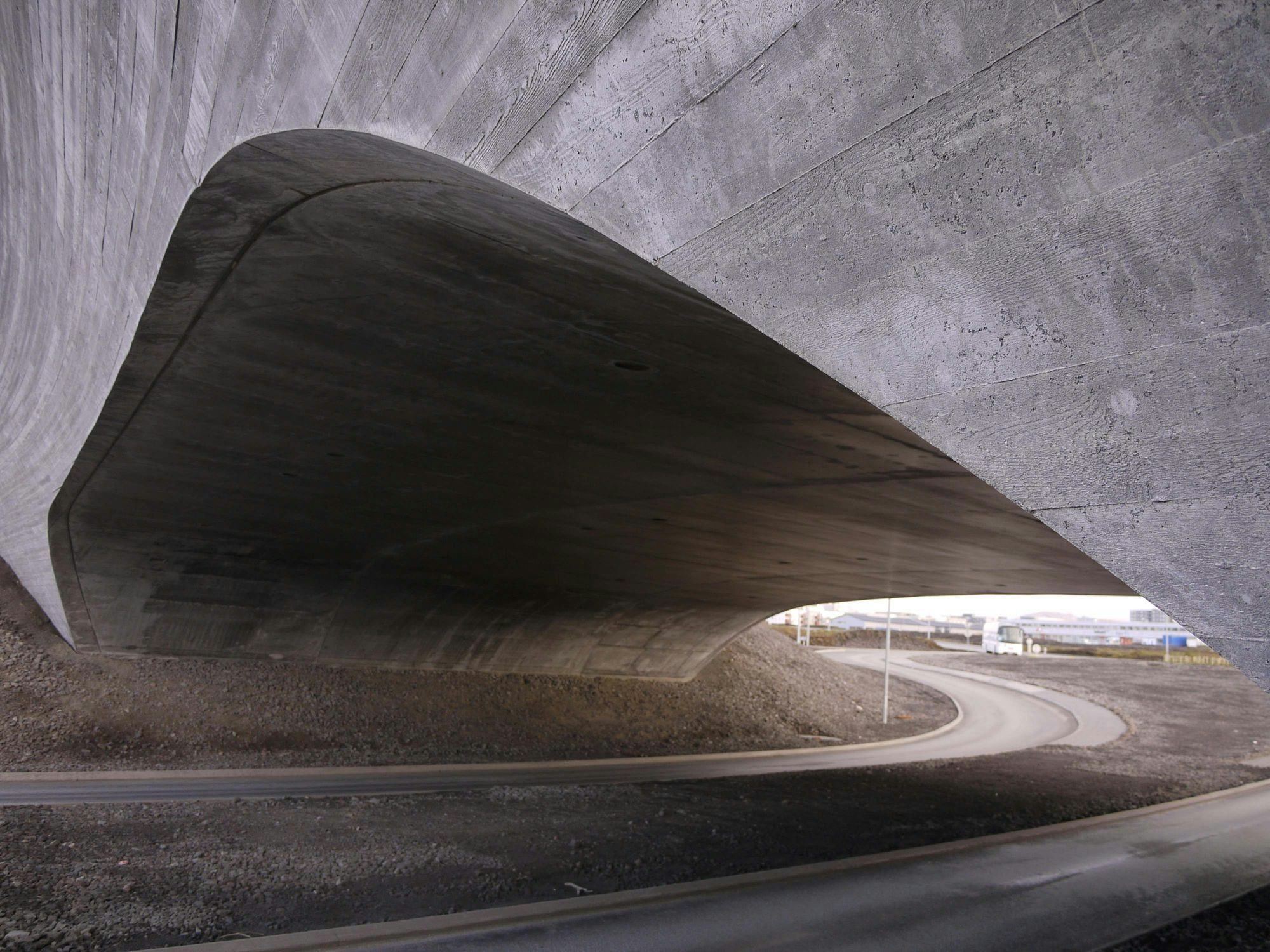 A tunnel like underpass with a smooth, dark interior that contrast with the light at the tunnel's end 