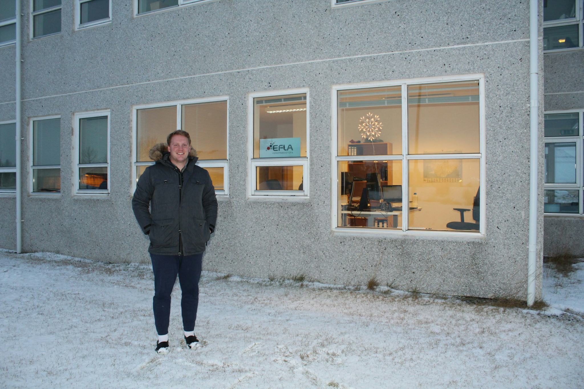 A man standing outside a building with windows that shows the interior space