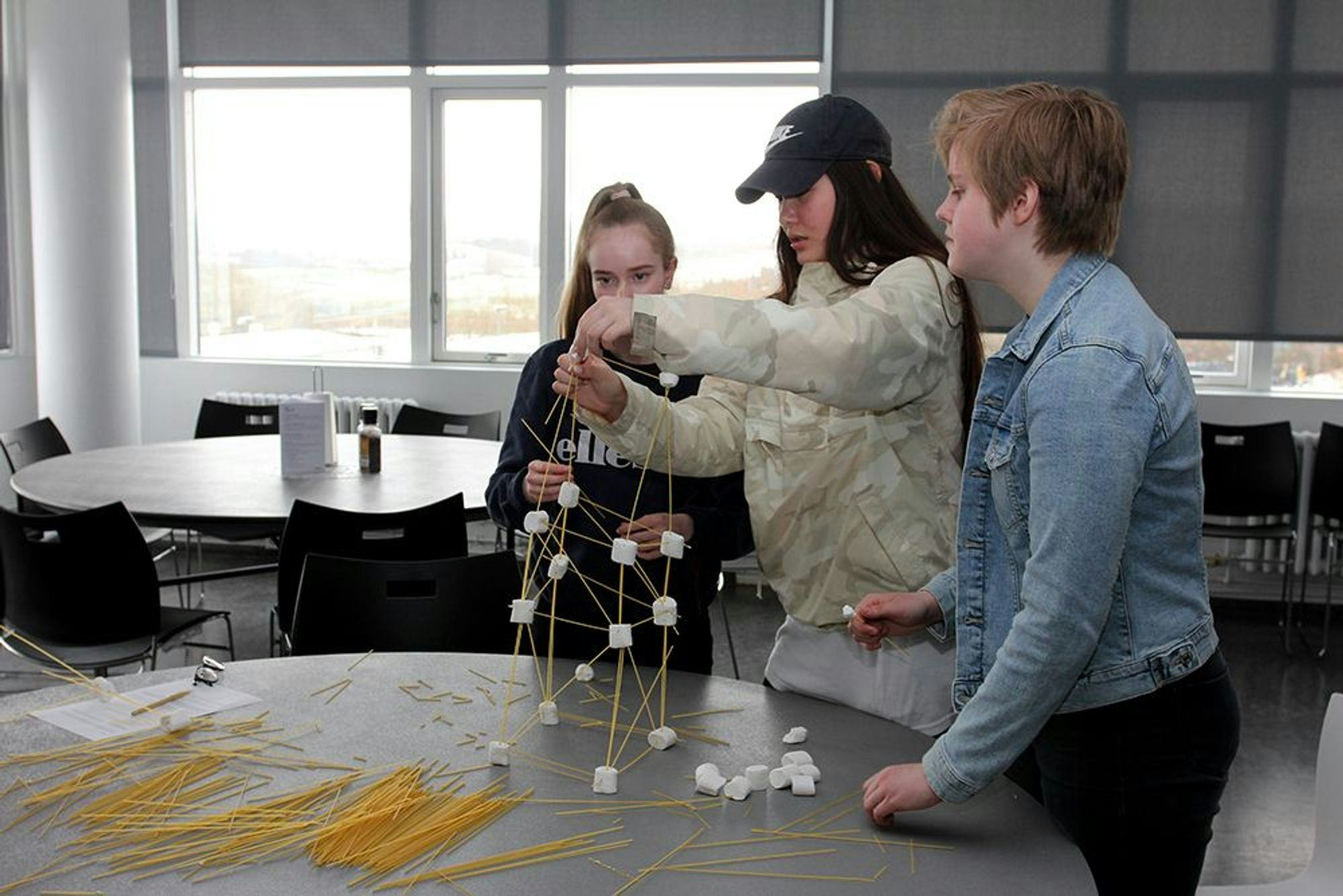 Three kids building some prototype using marshmallow and spaghettis 