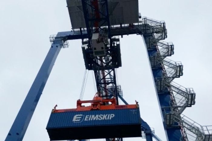 A large harbor crane lifting an EIMSKIP container